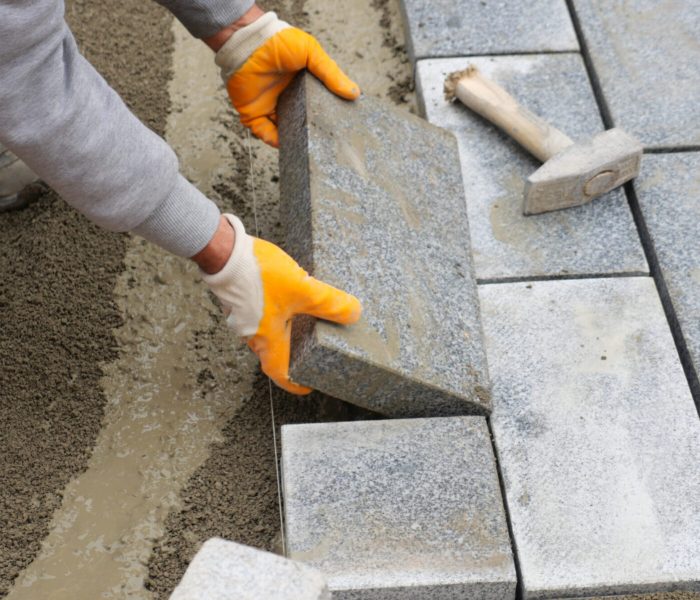a worker laying concrete bricks on each other for building a new sidewalk.